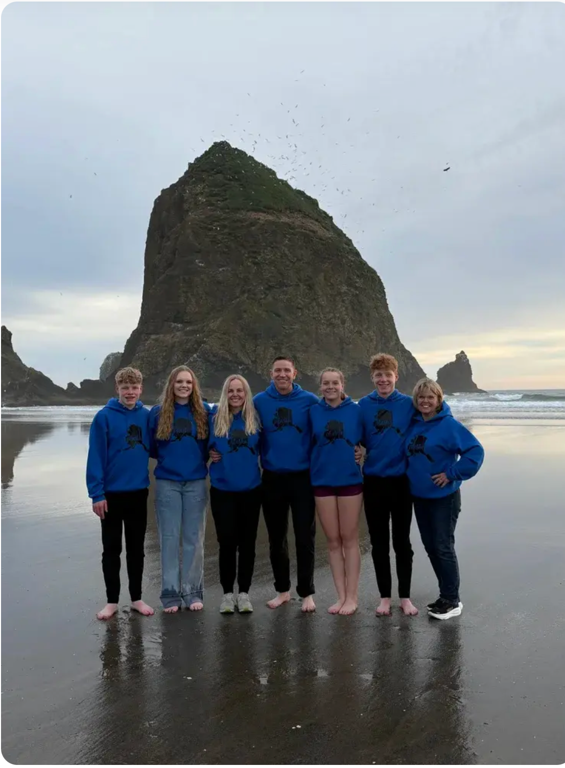 Rebecca and her family in matching blue hoodies on the beach in front of Haystack Rock